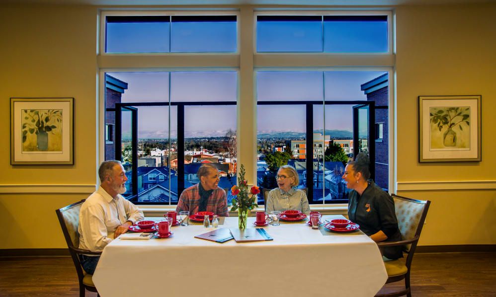 A group of people dining at a table with a scenic city view through large windows.