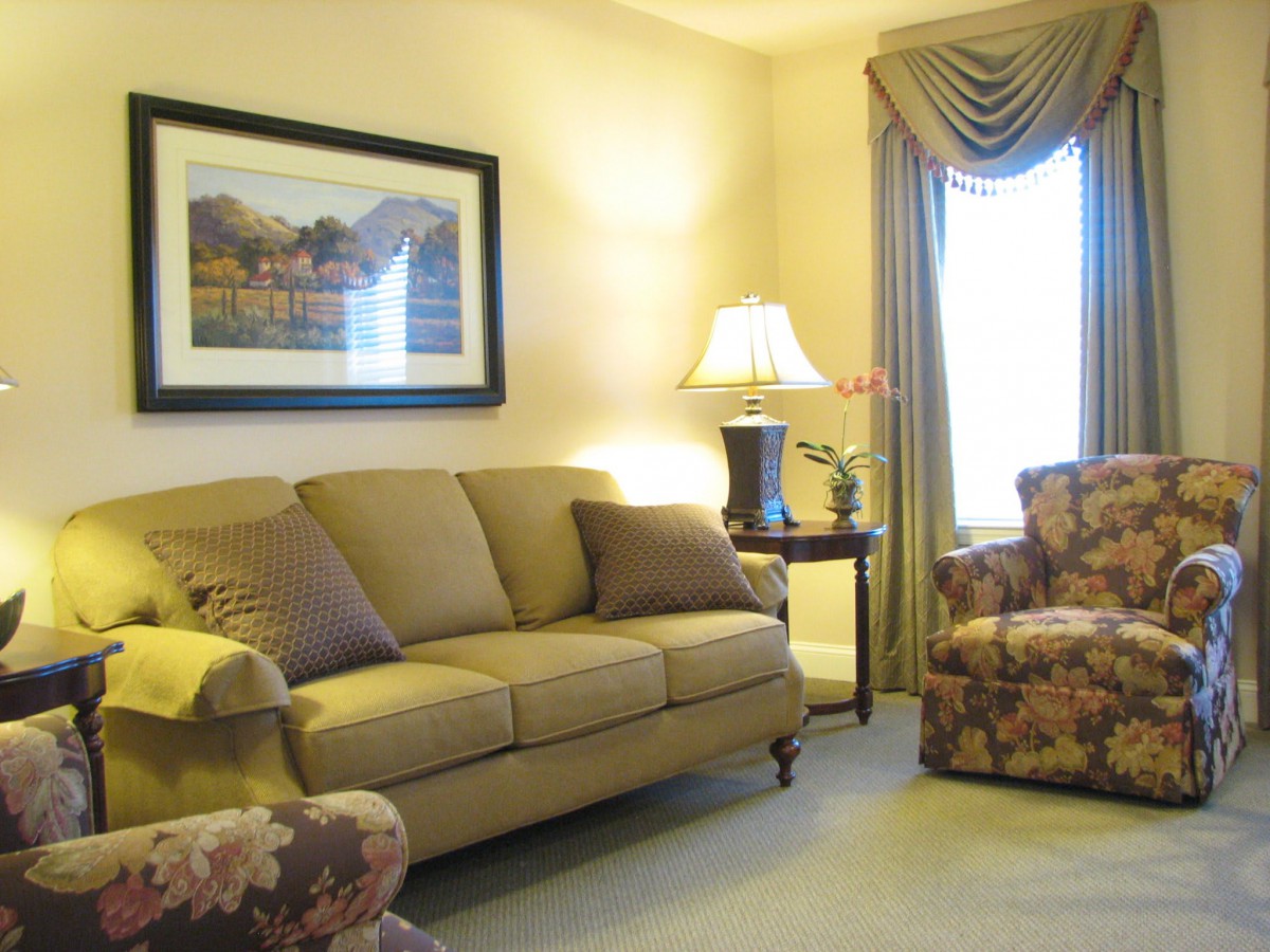 A cozy living room with a sofa, lamp, and artwork on the wall.