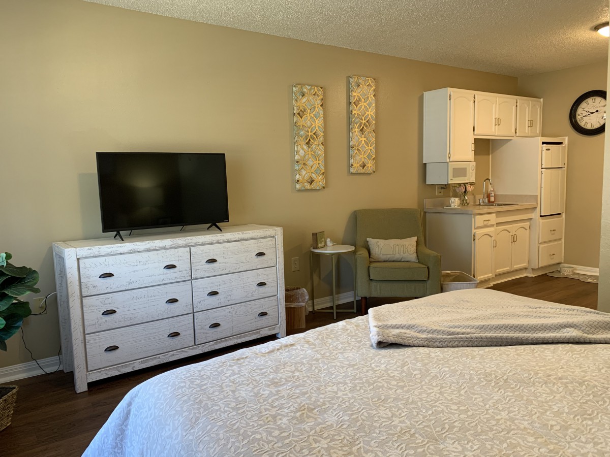 A cozy bedroom with a TV, dresser, and comfortable seating area.