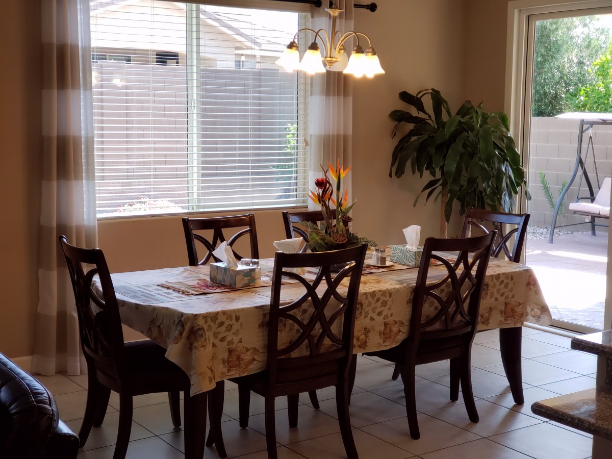 A cozy dining room with a table set for a meal, featuring elegant chairs, a tablecloth, and ambient lighting.