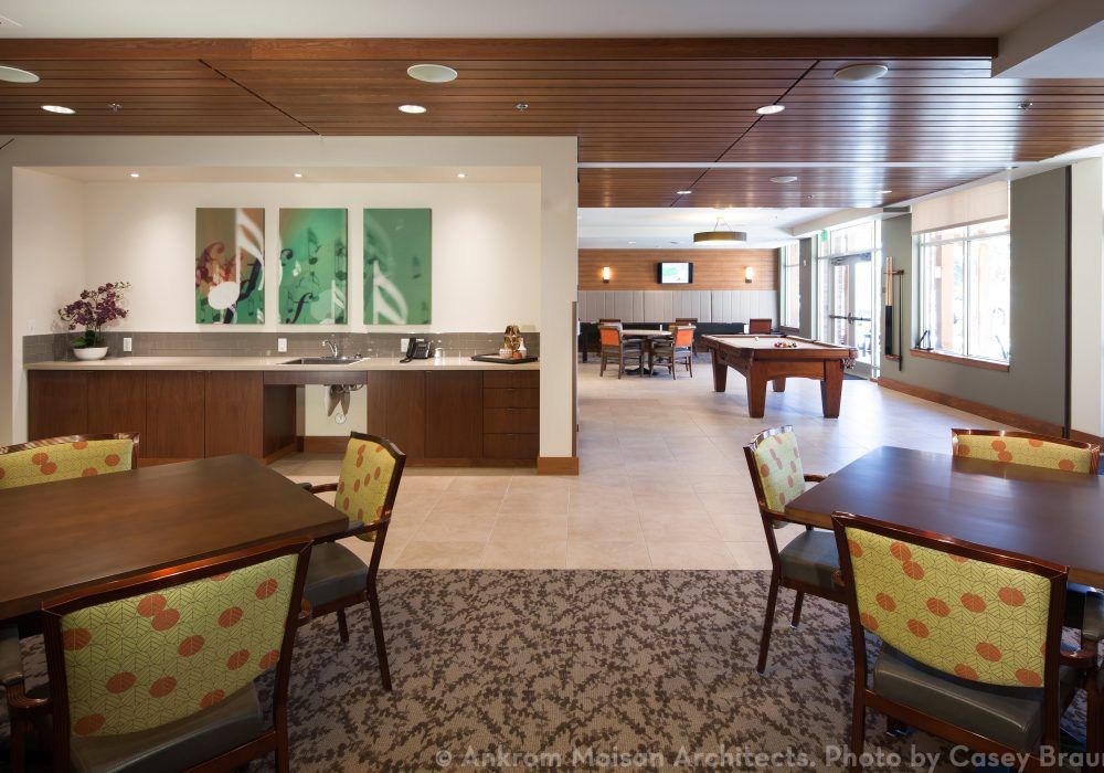 A modern recreation and lounge area with tables, chairs, and a pool table.