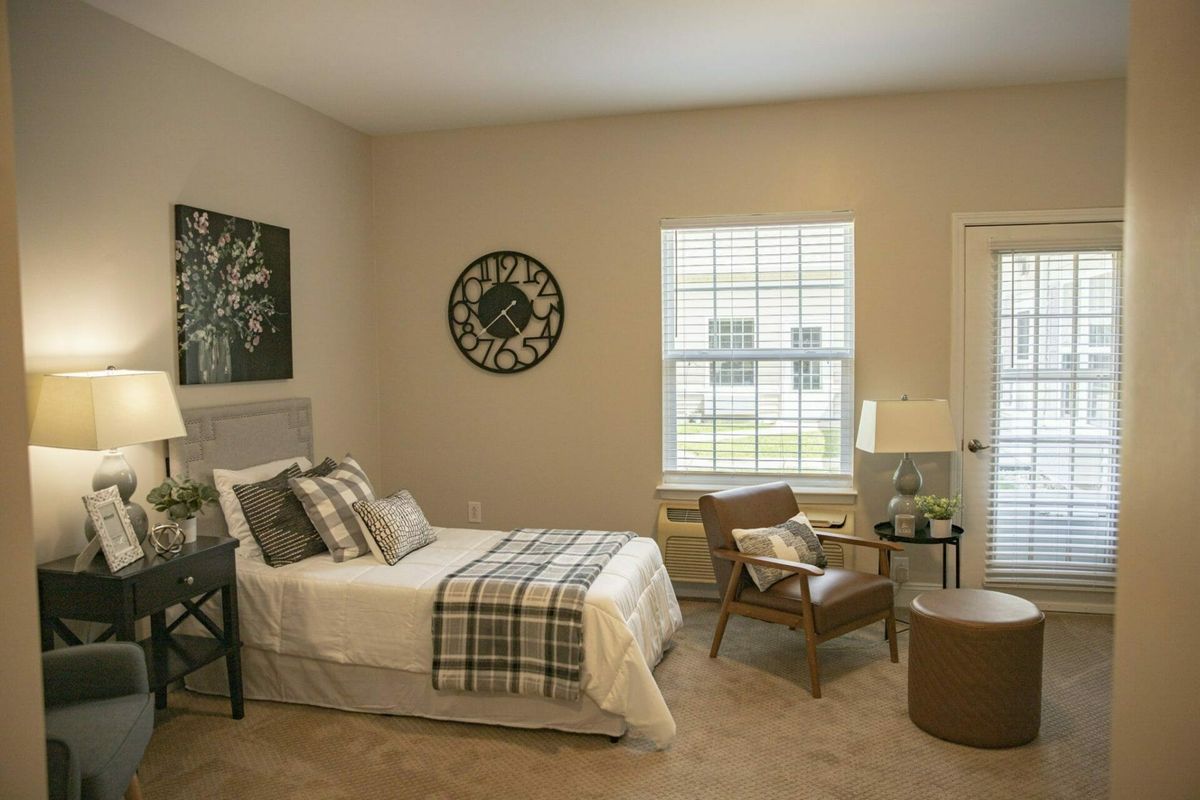 A cozy bedroom with a bed, chair, and decor items.