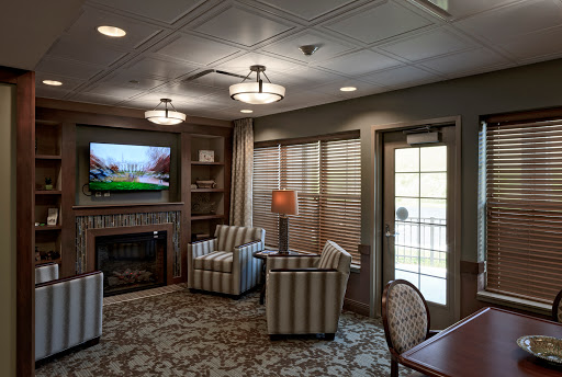 A cozy living room featuring striped armchairs, a television, and a warm fireplace.