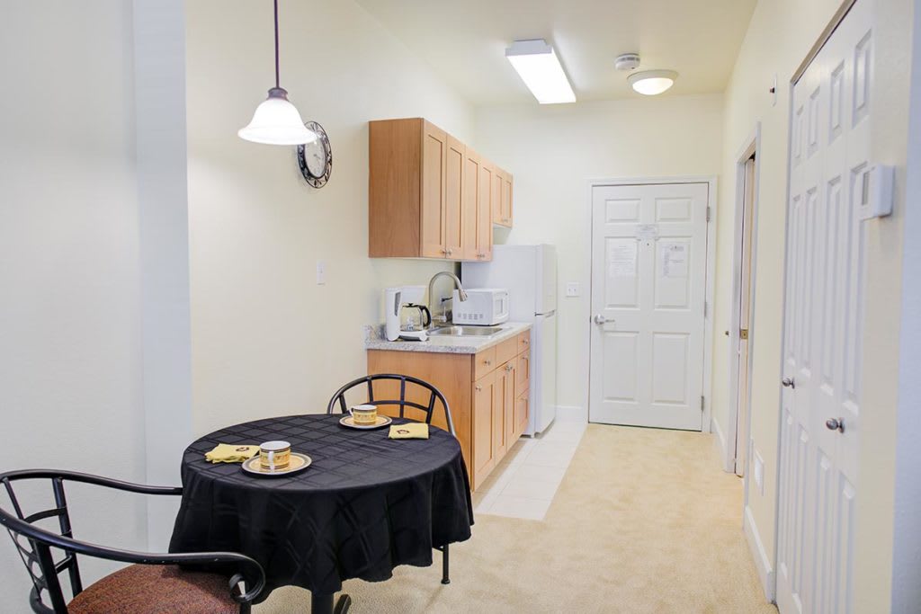 A compact kitchen area with wooden cabinets and a small dining table set for two.