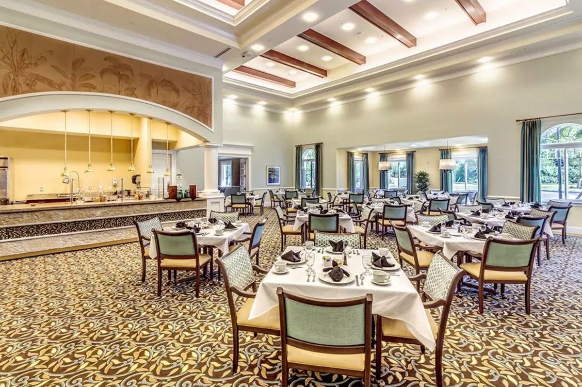 An elegant dining area with set tables and chairs, featuring warm lighting and sophisticated interior design.
