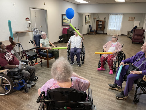 Residents engage in a fun and interactive activity with colorful balloons and pool noodles.