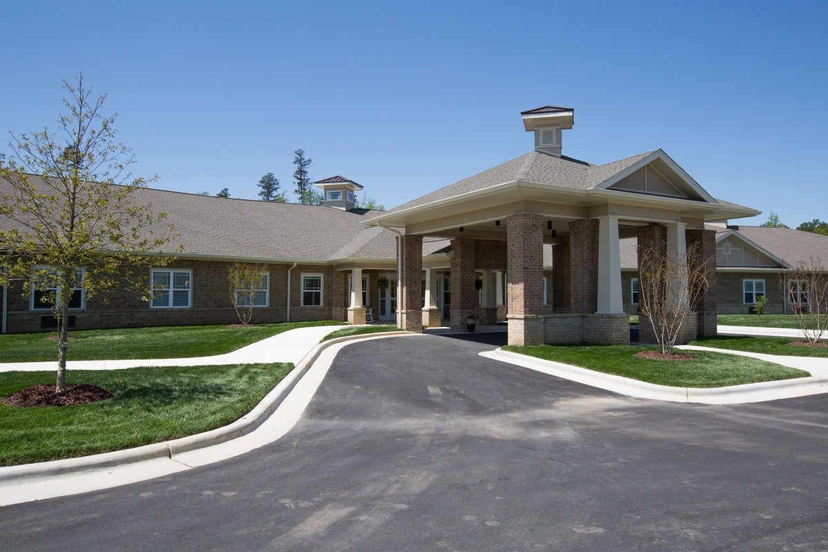 A building with a covered entrance and a driveway leading up to it.