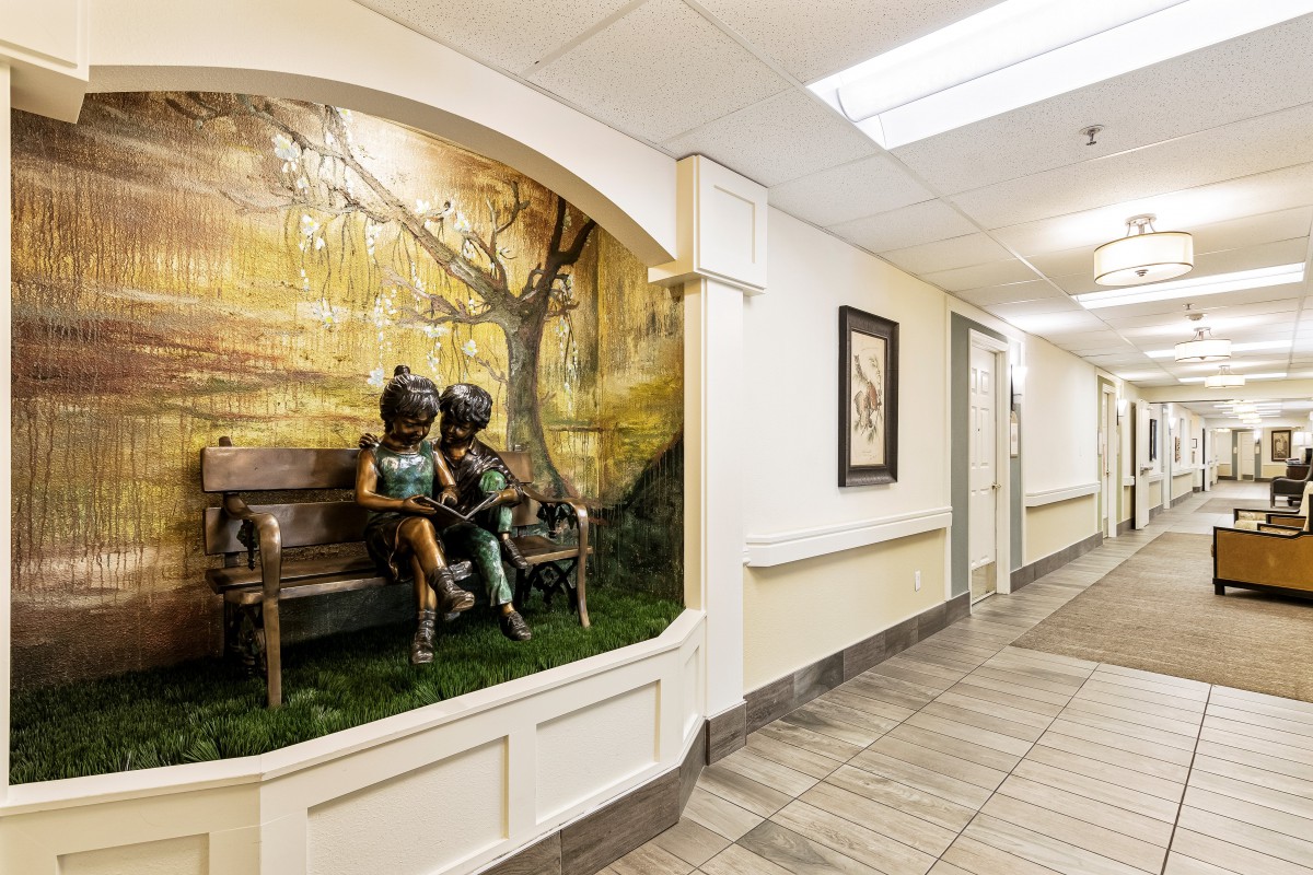 A hallway featuring a sculpture of children on a bench, embedded into the wall with decorative artwork behind it.