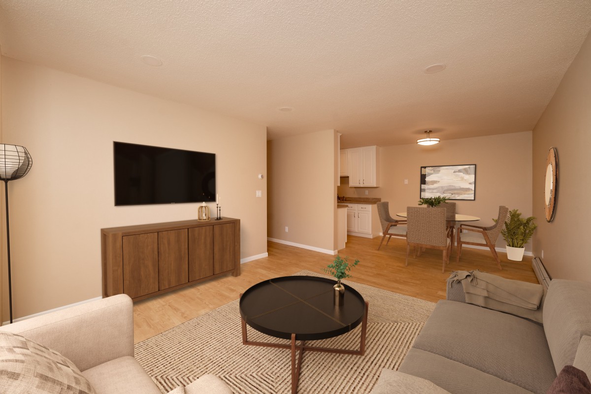 A modern living room with neutral tones, featuring a flat-screen TV, a coffee table, and an adjacent dining area.