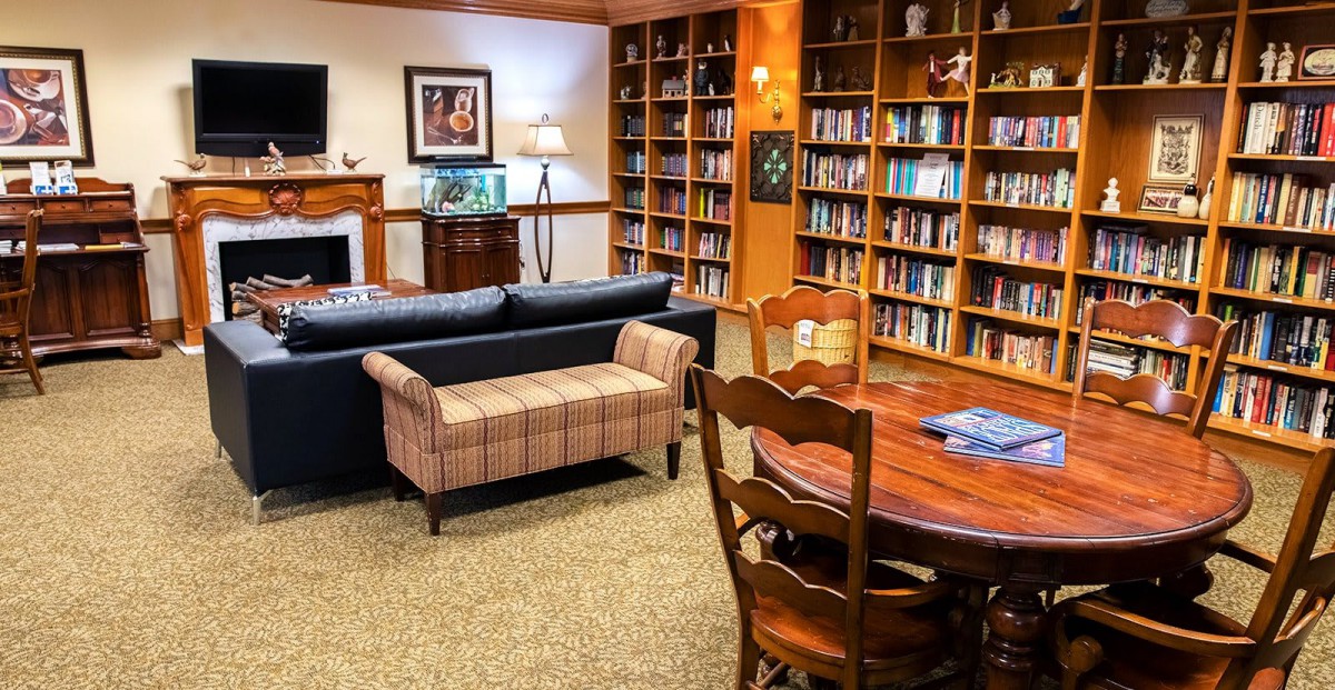A cozy library space with bookshelves, seating, and a reading table.
