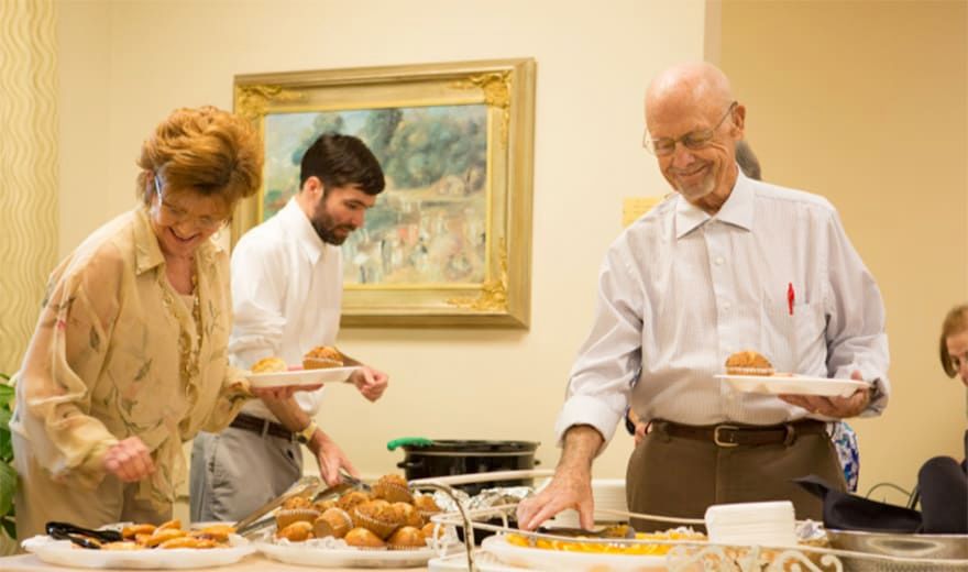 People serving themselves at a buffet during a gathering.