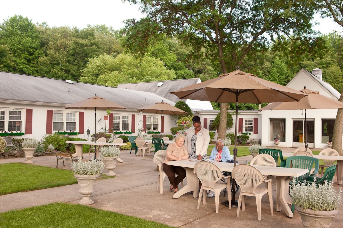 Seniors enjoying a relaxing time on a patio surrounded by trees.