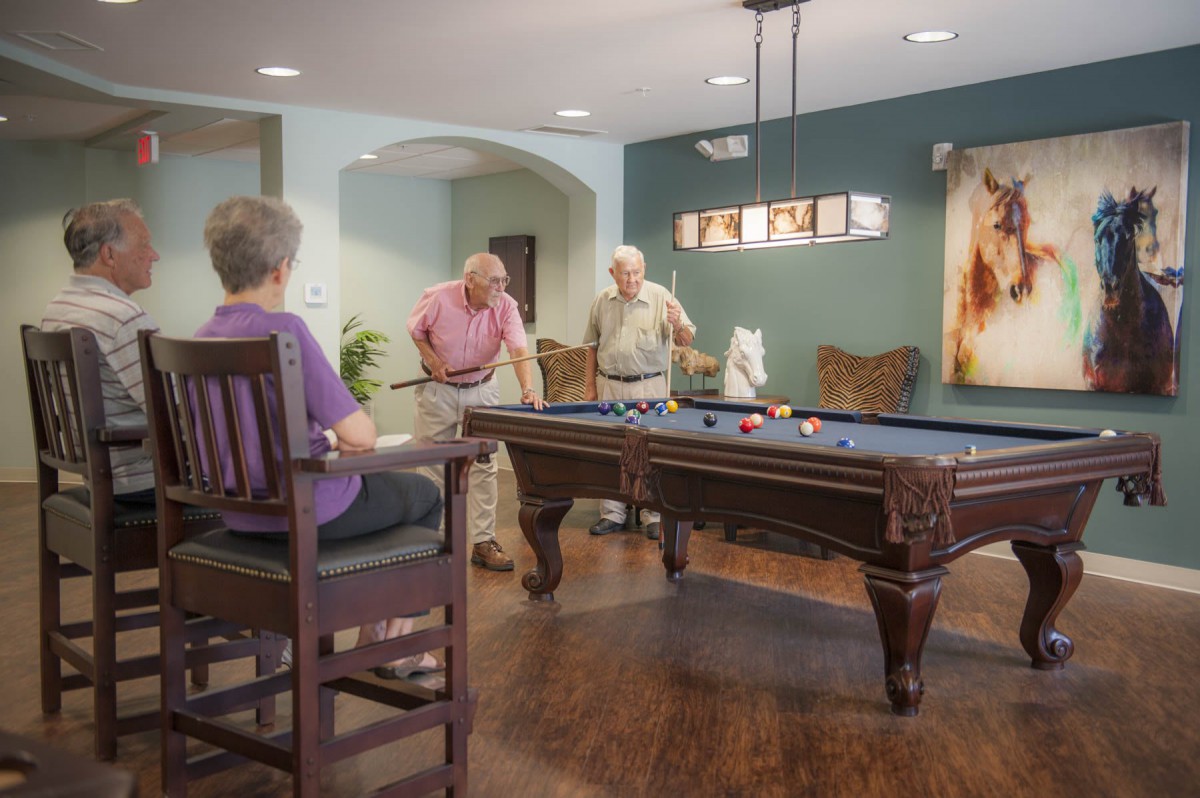 Seniors enjoying a game of billiards in a cozy indoor setting.