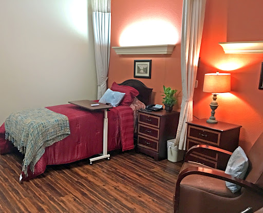 A cozy and warmly decorated bedroom featuring a neatly made bed, bedside lamp, and a touch of greenery.