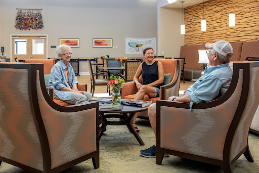 Three individuals engaged in a friendly conversation in a cozy living room setting.