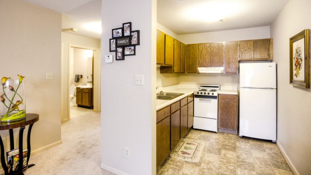 A compact kitchen with wooden cabinets and basic appliances in an apartment setting.