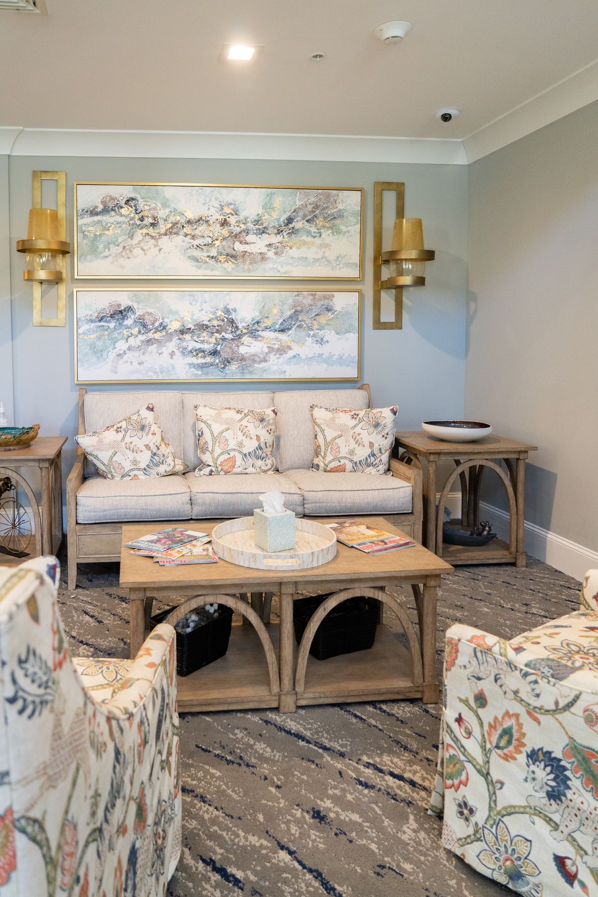A cozy living room with floral-patterned furniture and decorative artwork on the wall.