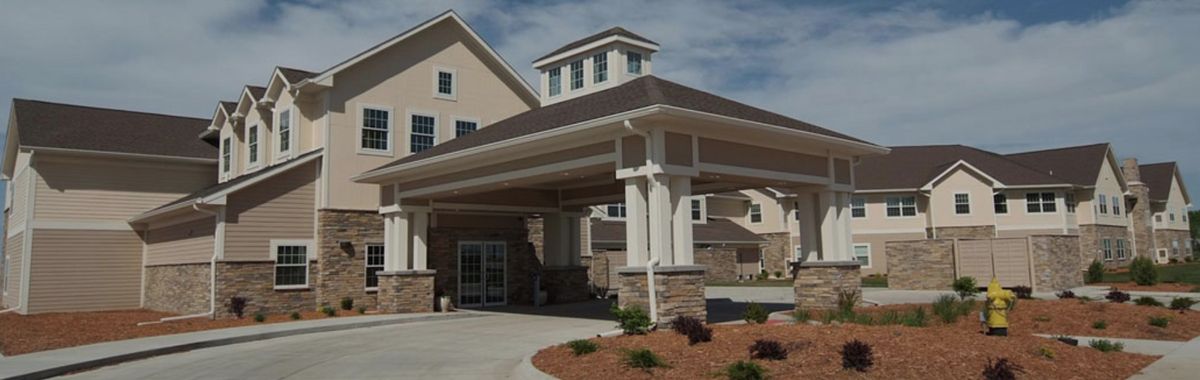 A modern residential building with a covered entrance and landscaped surroundings.