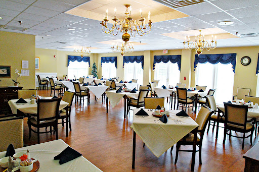 An elegantly arranged restaurant dining area featuring tables with white linens and a chandelier.