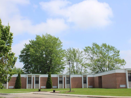 A school building surrounded by greenery under a partly cloudy sky.