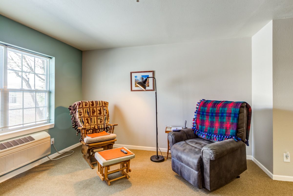 A cozy living room corner with an armchair, rocking chair, and a soft lamp.