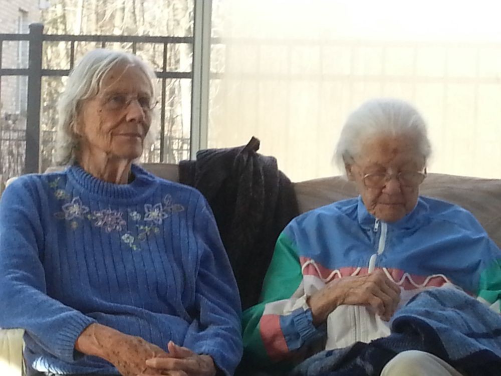 Two elderly women sitting indoors, one of them knitting.