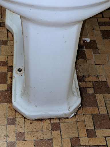 A close-up view of the base of a toilet, showing signs of wear on the surface.