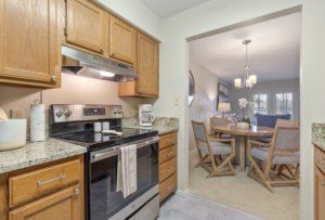 A cozy kitchen with wooden cabinets adjacent to a dining area with a round table and chairs.