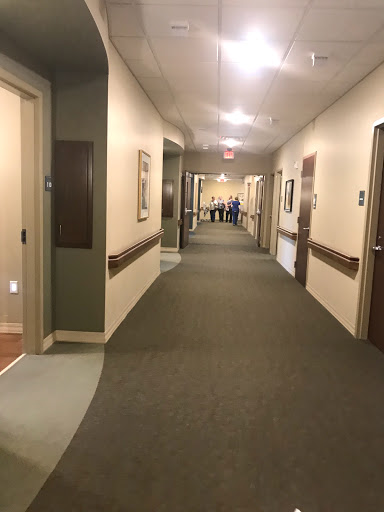 A spacious and well-lit hallway in a healthcare facility, featuring closed doors on either side.