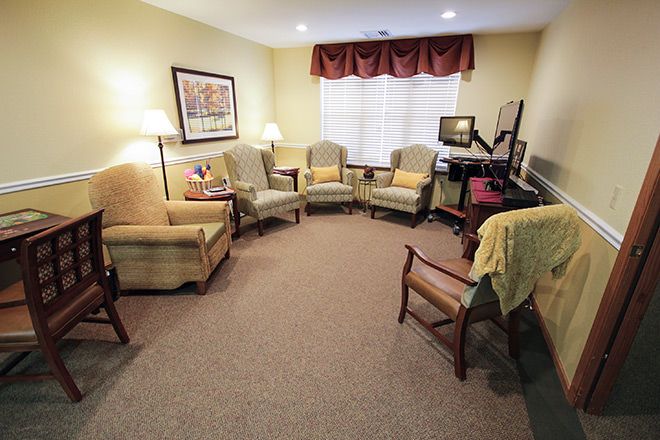 A cozy living room with multiple chairs arranged in a circle, featuring lamps and a warm color palette.