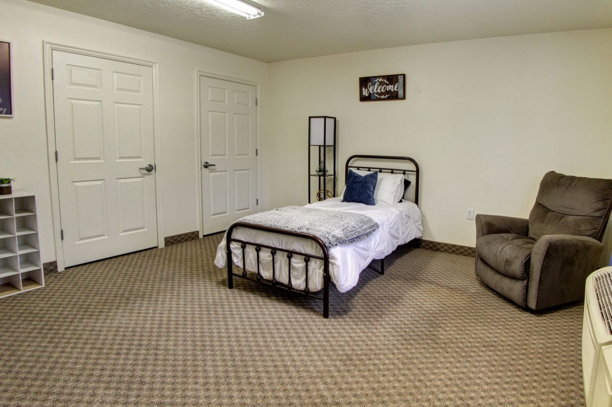 A minimalist bedroom featuring a single bed and carpeted flooring.