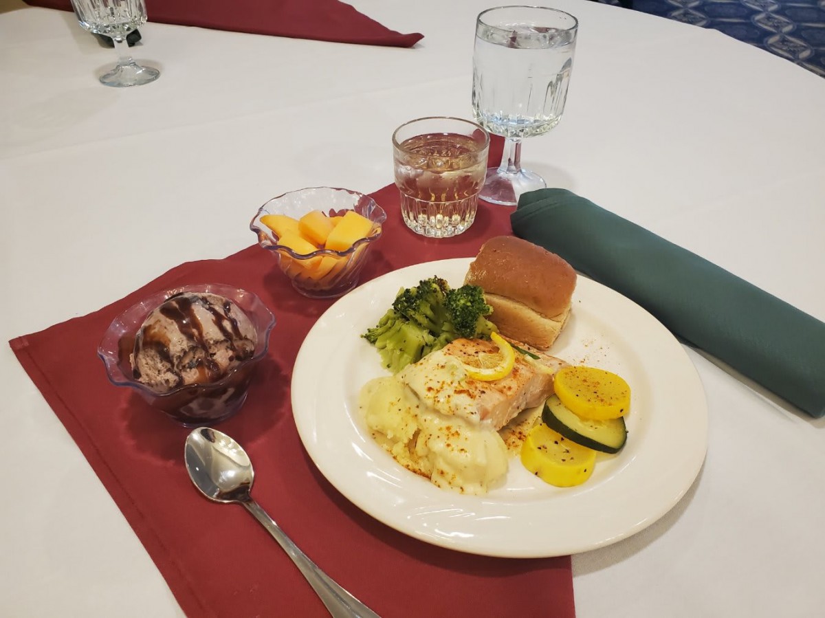 A table set with a meal consisting of various dishes, a dessert, and drinks.