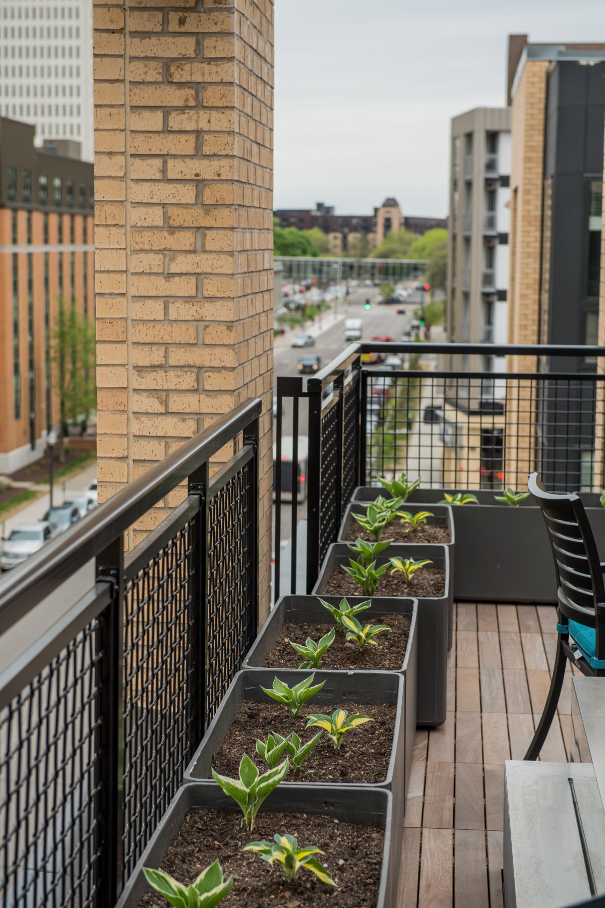 A modern urban balcony with plants and a view of the city street.