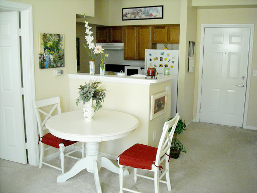 A bright and cozy dining area featuring a round white table with red cushions and elegant floral decor.