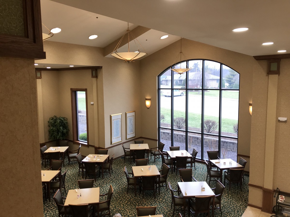 A spacious dining area with several tables and chairs, featuring large windows that allow natural light to fill the room.
