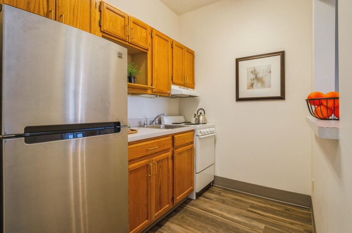 A compact kitchen with wooden cabinets and a stainless steel refrigerator.