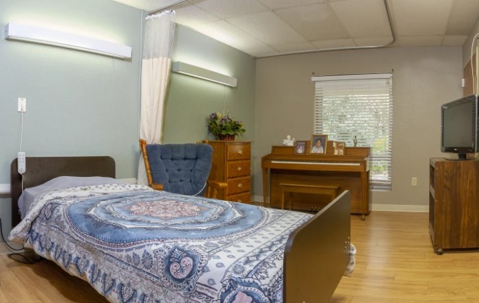A cozy bedroom featuring a bed with a patterned blanket, a piano, and elegant furniture.