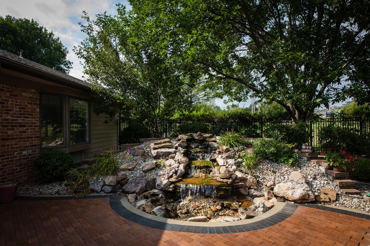 A serene garden with a cascading waterfall surrounded by lush greenery.