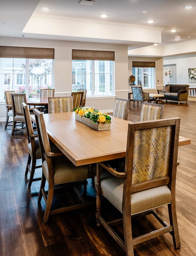 A well-lit dining room with a large wooden table and chairs, featuring a decorative centerpiece.