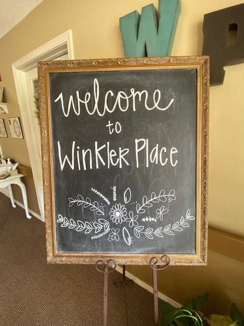 A decorative chalkboard sign that reads 'Welcome to Winkler Place'.