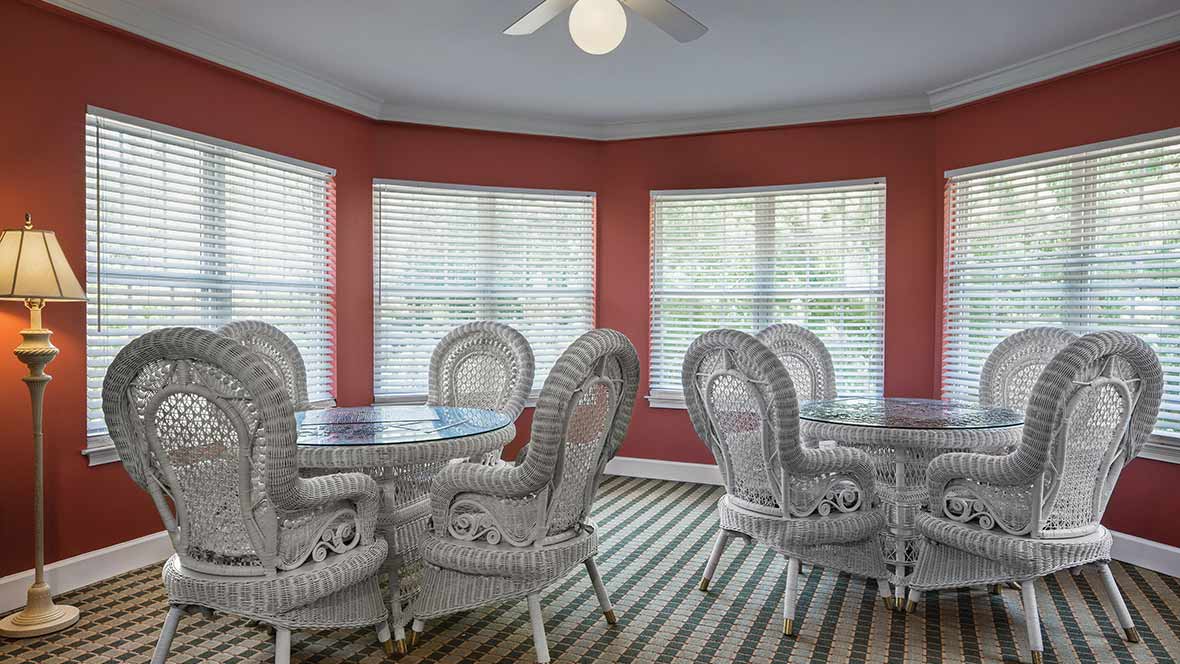 A bright dining area with wicker furniture and red walls.