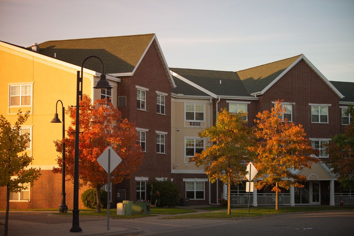 A condominium building surrounded by vibrant autumn trees at sunset.