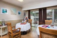 A cozy dining area with tables set for meals, featuring wooden chairs and decorative elements.