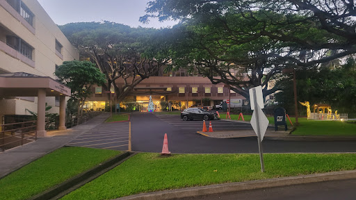 A serene view of a building surrounded by trees, featuring a parking lot and street signage in the evening light.