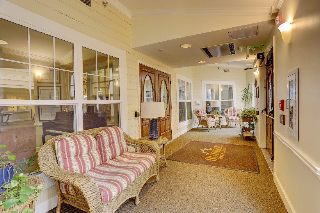A cozy sunroom with wicker furniture and large windows.