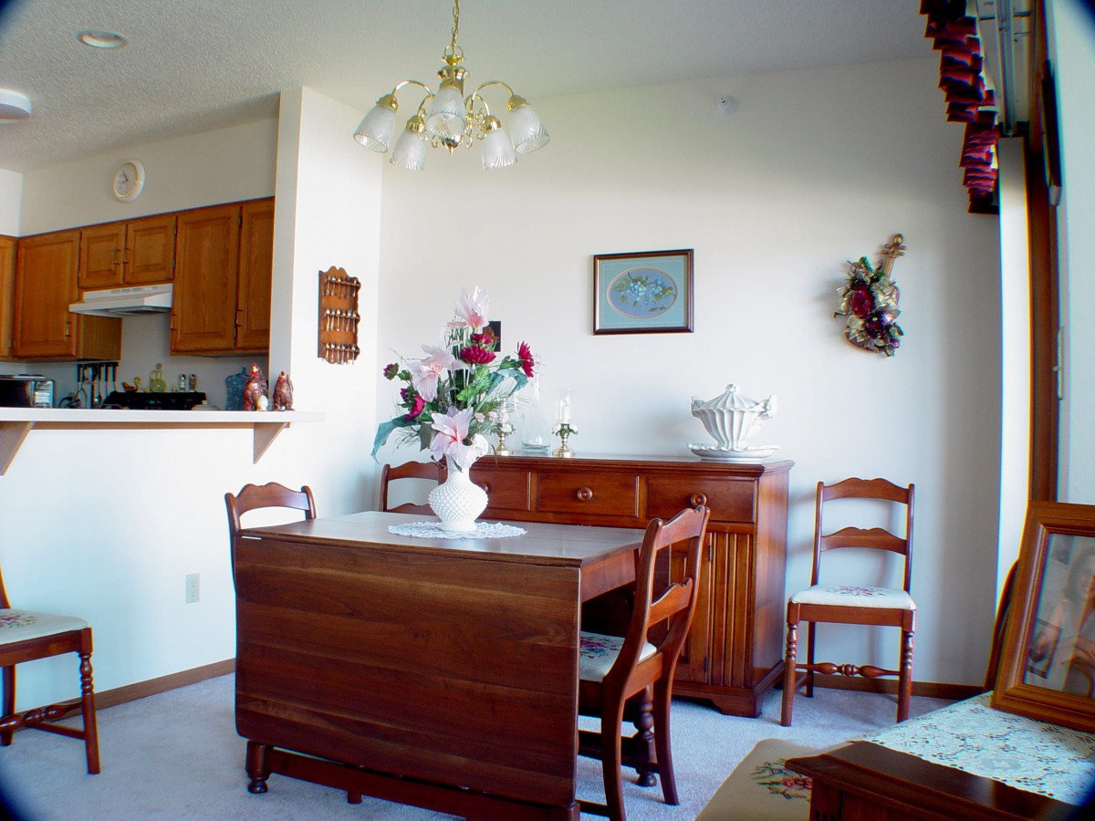 A cozy dining room with wooden furniture, including a table set for four and a decorative vase of flowers.