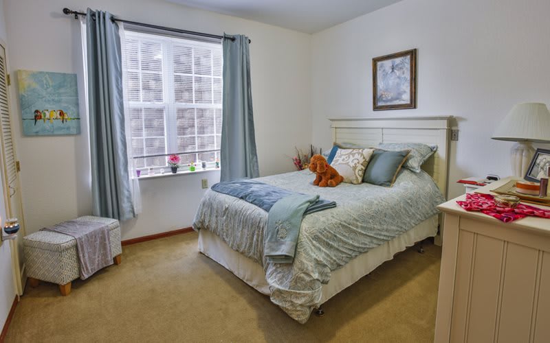 A cozy bedroom with a neatly made bed, light blue curtains, and soft lighting.