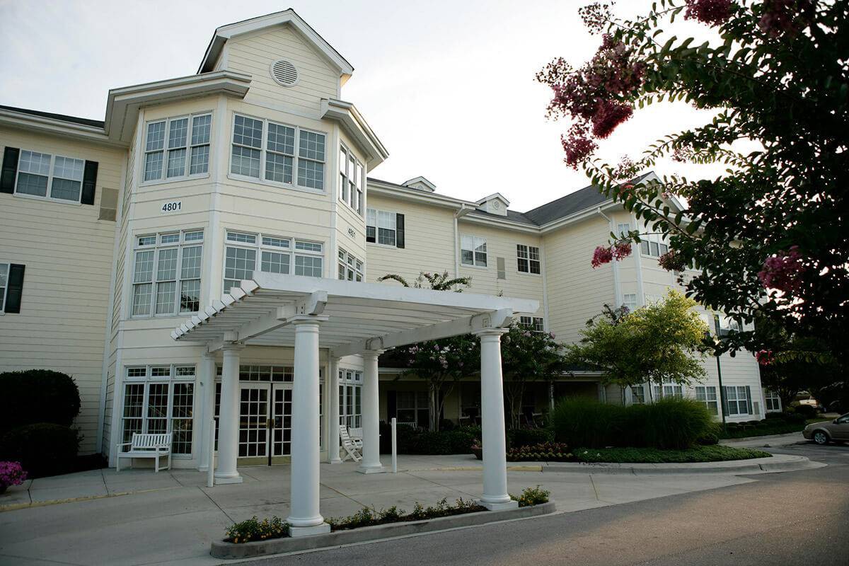 A view of a residential building with a covered entrance and landscaped surroundings.