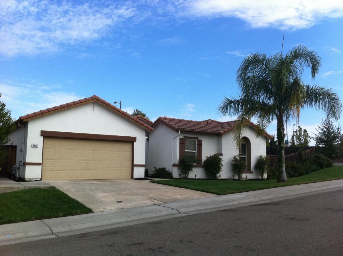 A suburban house with a garage and palm trees in the front yard.
