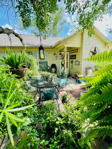 A serene garden setting featuring lush greenery and a cozy patio.